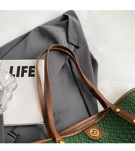 Détail du cabas tissé vert foncé avec bandoulières en cuir marron et logo doré