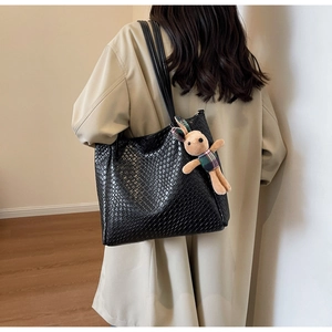 Detail showing large black crocodile pattern tote bag with rabbit pendant accessory