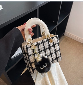 Dettaglio della borsa in tweed pied-de-poule con manico bianco e ciondolo mostro peluche