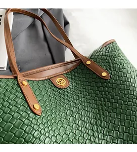 Détail du sac cabas tissé vert avec poignées en cuir marron et boucle en métal doré