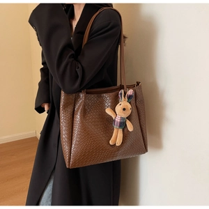 Close-up of deep brown woven texture tote bag featuring a cute plush bunny charm