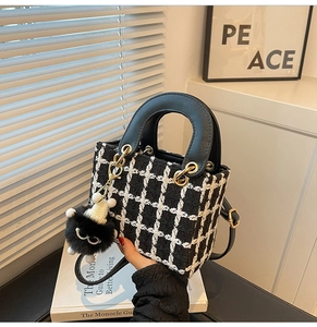 Dettaglio della borsa a mano in tweed a scacchi con manici in pelle e charm in peluche