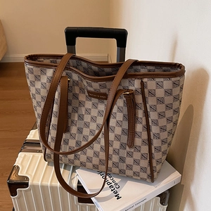 Large capacity vintage plaid tote bag with brown leather handles on a white suitcase