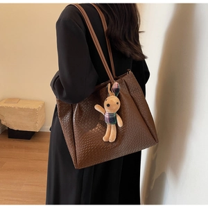 Close-up of a large woven brown tote bag with a cute rabbit plush charm and long straps