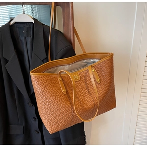 Détail du grand cabas marron en cuir texturé avec fines lanières et logo en métal