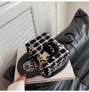 Dettaglio borsa a mano in tweed bianco e nero con manico in pelle e ciondolo di peluche