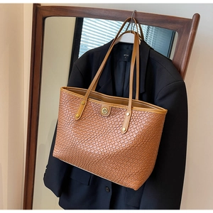 Détail du cabas marron avec texture tressée et logo DM doré dans un décor de style de vie
