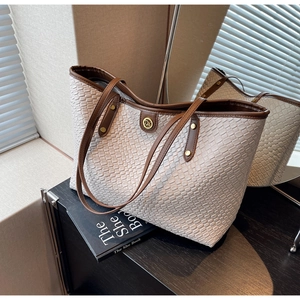 Détail du sac cabas tissé avec garniture en cuir et logo métallique DM élégant