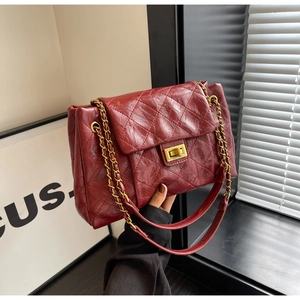 Detailed close-up of quilted wine red leather chain bag with golden metal twist lock