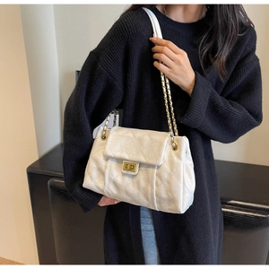 Detail of white quilted handbag featuring gold twist lock and woven chain strap