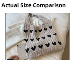 Comparaison de taille d'un cabas tricoté à motifs de cœurs avec un téléphone sur tissu