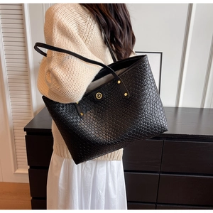 Détail du sac cabas tissé noir avec logo métallique doré et rivets de poignée renforcés