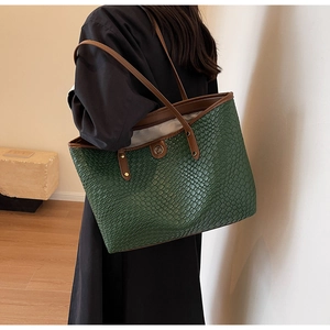 Vue détaillée du sac cabas en cuir tressé vert avec des anses marron sur l'épaule