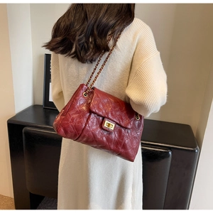 Detailed back view of a dark red quilted leather chain strap crossbody bag on a model
