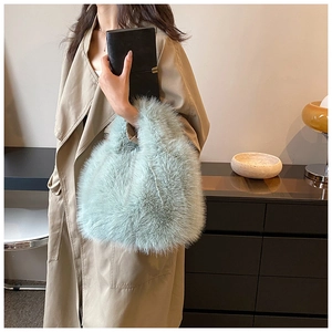Detail of mint green fuzzy handbag held by model in stylish trench coat outfits