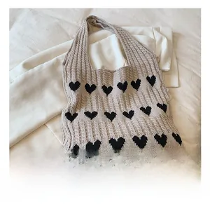 Détails du motif jacquard à cœurs sur un sac fourre-tout en maille beige et côtelée