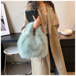 Close-up of soft light green faux fur handbag texture with fluffy handle on beige coat