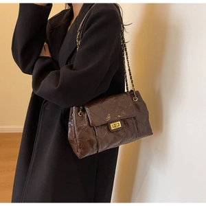 Macro shot of dark brown quilted leather texture and golden metal twist lock detail