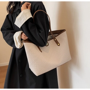 Détail d'un grand sac cabas crème avec poignées brunes et texture croco sur le mannequin