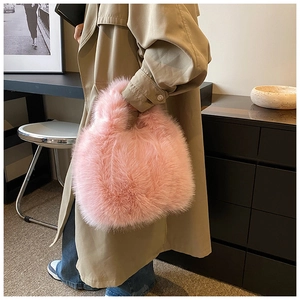 Detailed view of plush pink faux fur handbag styled with a winter coat and indoor decor