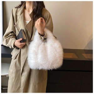 Detail of soft white faux fur handbag featuring plush texture and ergonomic top handle