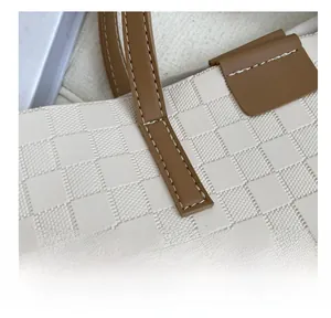 Macro view of meticulous white stitching and texture on checkered tote bag straps