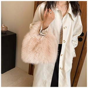 Detail of soft beige faux fur handbag with plush texture held by a model in a trench coat