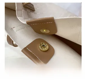 Detail of strong magnetic closure and brown leather trim on checkered tote bag
