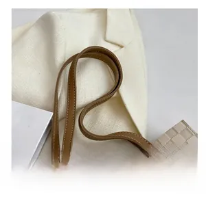 Detail view of beige checkered tote bag with brown leather strap and fashion label