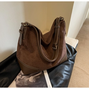 Detail of a large brown suede tote bag with contrast stitching and metal hardware buckle
