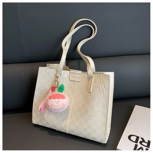 Detail of white woven tote bag with FASHION buckle and pink peach plush pendant decoration