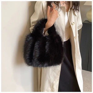 Detail of soft black faux fur handbag held by model wearing a beige trench coat
