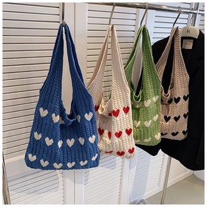Gros plan de sacs cabas en tricot avec motifs de cœur en bleu, crème, vert et camel