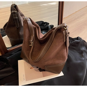 Detail of hobo bag featuring dark brown suede and smooth leather with contrast stitching