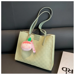 Detail of mint green tote bag with checkered texture and plush peach pendant charm