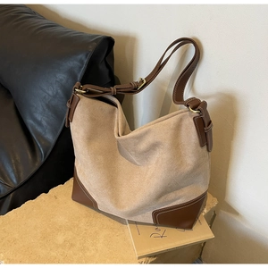 Detail of beige suede and brown leather tote bag with contrast stitching on stone base