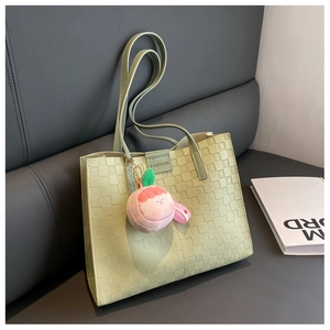 Detail of light green checkered tote bag with a pink peach plush charm and fashion strap
