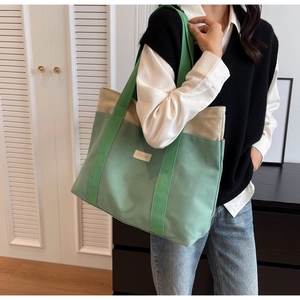 Détail d'un grand sac cabas en toile avec bandoulière verte et écusson en cuir SHUIHUO