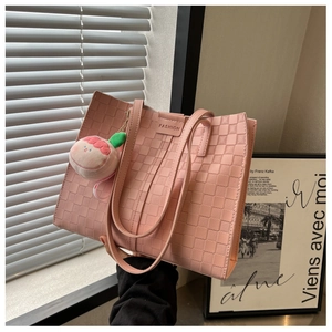 Detailed shot of pink woven tote bag with square texture and a peach plush charm