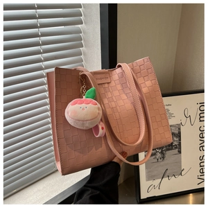 Detailed close-up of pink checkered woven tote bag with cute peach plush charm