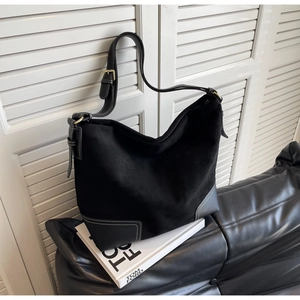 Detail of black suede hobo bag with contrast white stitching and gold metal buckle