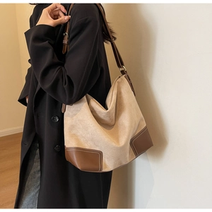 Detailed view of tote bag with beige canvas and brown leather strap on model