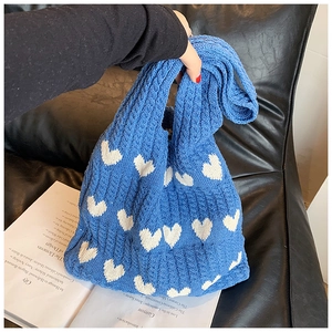 Gros plan sur le sac fourre-tout en tricot bleu avec motifs cœurs blancs et texture douce
