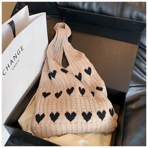 Détail de texture du sac cabas en tricot beige à motifs cœurs dans son coffret cadeau