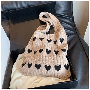 Détail du sac cabas en maille beige à cœurs avec texture côtelée dans une boîte