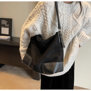 Detail of black suede tote bag with contrast stitching and adjustable leather strap