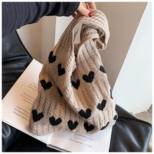 Gros plan sur la texture épaisse en maille torsadée d'un sac cabas beige à cœurs