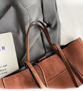 Detail of brown faux suede tote bag featuring white double stitching on leather handles