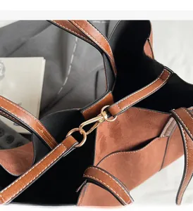 Detail of brown suede tote bag featuring contrast stitching and gold metal hardware hook