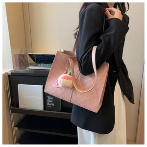 Pink woven tote bag with a cute peach plush charm shown on a shoulder strap